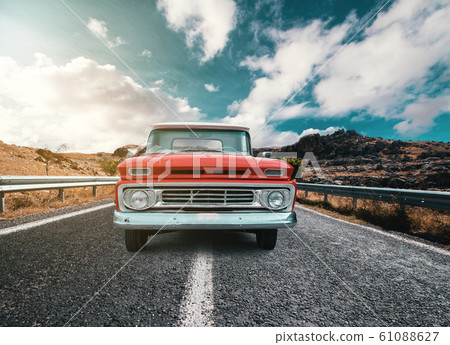 A Classical automobile on a journey on the country raod against the cloudy and blue sky A Classical automobile on a journey on the country raod against the cloudy and blue sky 61088627