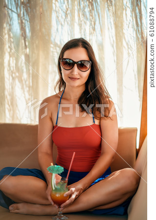 Young woman relaxing with her drink in a pergola on a vacation near to the sea Young woman relaxing with her drink in a pergola on a vacation near to the sea 61088794