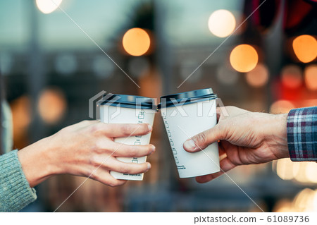 a couple is toasting with paper cup and drink coffee 61089736