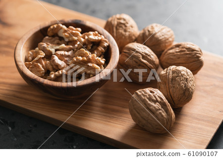 Walnuts in wooden bowl on olive board 61090107