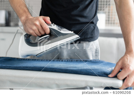 A guy ironing clothes before going outside 61090208