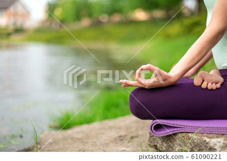 A young sports girl practices yoga on a green lawn A young sports girl practices yoga on a green lawn 61090221