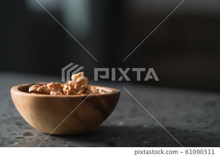 Walnuts in wooden bowl on terrazzo countertop with copy space Walnuts in wooden bowl on terrazzo countertop with copy space 61090311