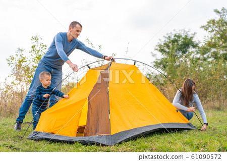 Happy family with little son set up camping tent. Happy family with little son set up camping tent. 61090572