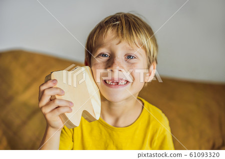 A boy, 6 years old, holds a box for milk teeth. Change of teeth 61093320