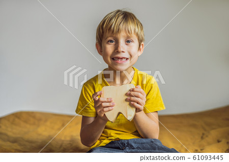 A boy, 6 years old, holds a box for milk teeth. Change of teeth 61093445