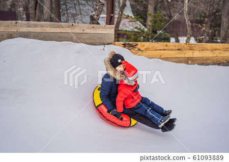 mom son ride on an inflatable winter sled tubing. Winter fun for the whole family 61093889