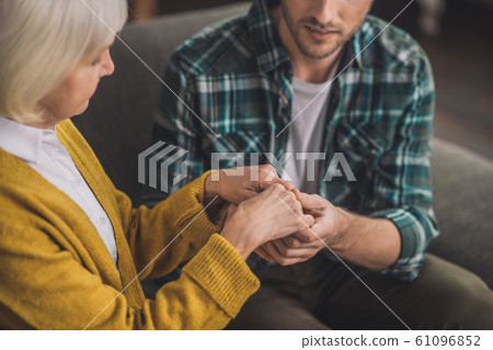 Young handsome man holding his moms hands with love Young handsome man holding his moms hands with love 61096852