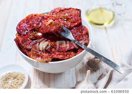 Dried tomatoes with garlic in bowl on white Dried tomatoes with garlic in bowl on white 61096930
