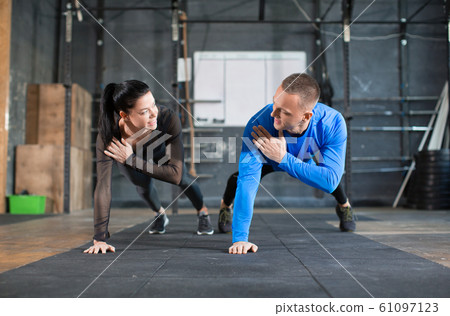 Man and woman doing pushups at training in gym. Man and woman doing pushups at training in gym. 61097123