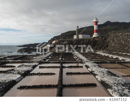 View of Fuencaliente salinas or saltworks and two lighthouse, old stone and white-red striped with volcanic rock field.La Palma, Canary Islands. Ocean, blue sky white clouds. 61097152
