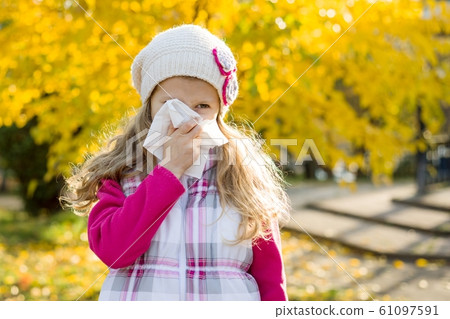 Girl child with cold rhinitis on autumn background, flu season, allergy runny nose Girl child with cold rhinitis on autumn background, flu season, allergy runny nose 61097591