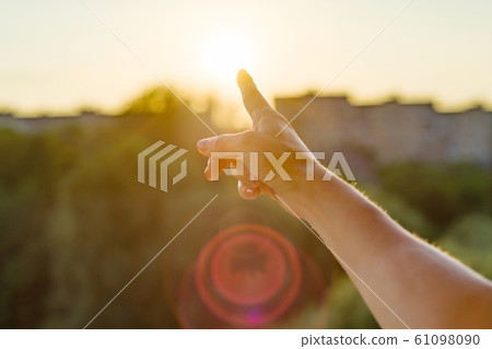 Gesture with the index finger towards the sunset. Background sky, silhouette of the city, sunset 61098090