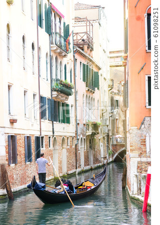 Men gondoliers drive gondolas with tourists in Venice in Italy. 61098251