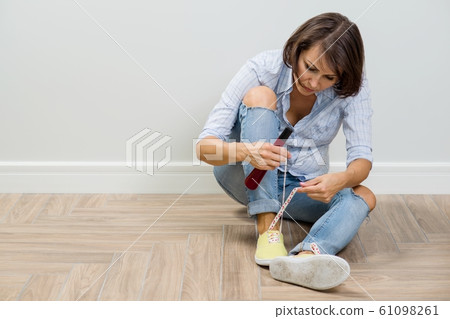 The woman is going to leave the house, shoes sneakers, tying shoelaces 61098261