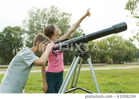 Children teenagers with telescope look at the sky in nature Children teenagers with telescope look at the sky in nature 61098299