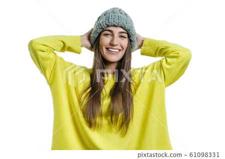 Young cheerful beautiful woman in yellow sweater and gray big loop knitted beanie hat looking at the camera on white isolated background 61098331
