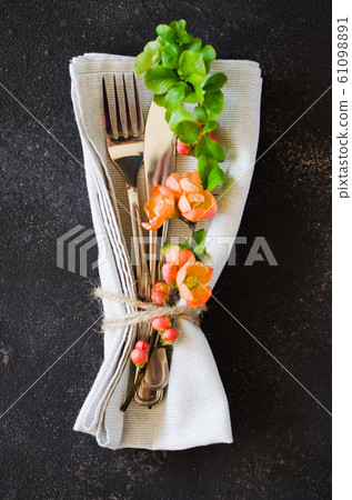 Vintage table setting with delicate flowers on a linen napkin on on rustic shabby table, close-up. 61098891