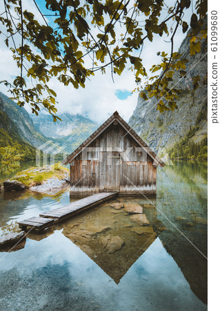 Idyllic view of traditional old wooden boat house reflecting in mountain lake in the Alps Idyllic view of traditional old wooden boat house reflecting in mountain lake in the Alps 61099680