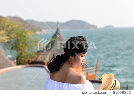突出在夏天亞洲海岸線的海運背景的一個少婦 突出在夏天亞洲海岸線的海運背景的一個少婦 61099808