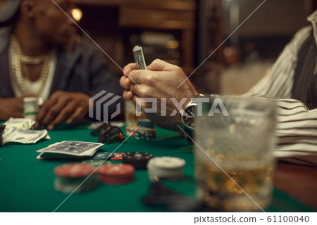 Poker players place money bets on gaming table 61100040