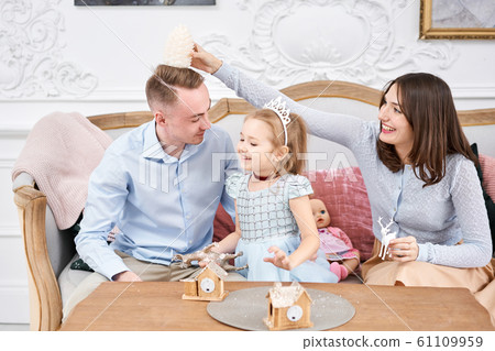 Loving family Mom and dad, little daughter . Parents and baby child having fun. Merry Christmas and Happy New Year. Cheerful pretty people. Loving family Mom and dad, little daughter . Parents and baby child having fun. Merry Christmas and Happy New Year. Cheerful pretty people. 61109959