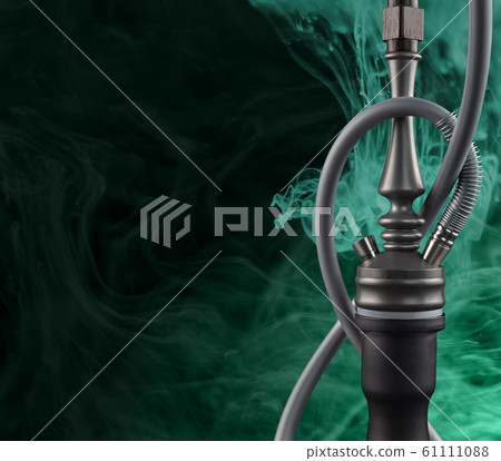Modern hookah shrouded in mysterious aqua menthe smoke on a black background with a place for text. Modern hookah shrouded in mysterious aqua menthe smoke on a black background with a place for text. 61111088
