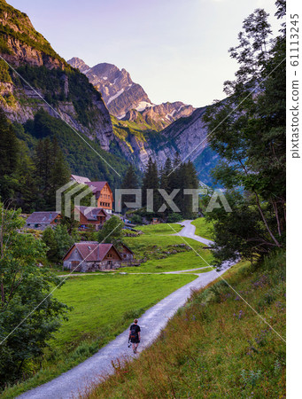 Tourist walks down the path to Seealpsee lake in the Swiss Alps Tourist walks down the path to Seealpsee lake in the Swiss Alps 61113245