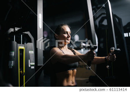 Sexy strong muscular female with perfect fitness body works out on gym equipment 61113414