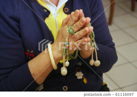 Woman press the hands together at the chest in sign of respect and hold prayer beads on hands for praying Woman press the hands together at the chest in sign of respect and hold prayer beads on hands for praying 61116097