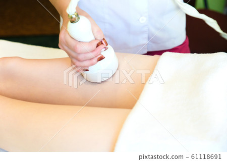 Body massage with cavitation. Young girl on massage table anti cellulite massage Body massage with cavitation. Young girl on massage table anti cellulite massage 61118691