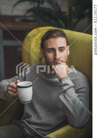Young bearded handsome man with cup looking thoughtful 61119177