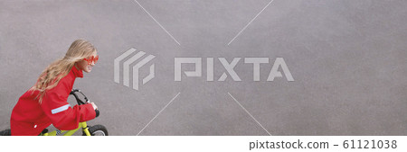 Young blonde girl in red jacket riding bike Young blonde girl in red jacket riding bike 61121038