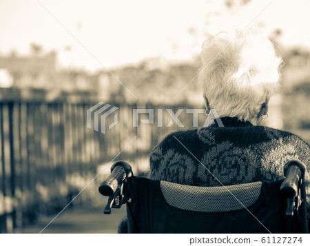 Picture of lonely old woman sitting on the wheelchair while looking at sunlight. Picture of lonely old woman sitting on the wheelchair while looking at sunlight. 61127274