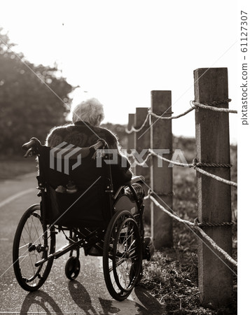 Picture of lonely old woman sitting on the wheelchair while looking at sunlight. Picture of lonely old woman sitting on the wheelchair while looking at sunlight. 61127307