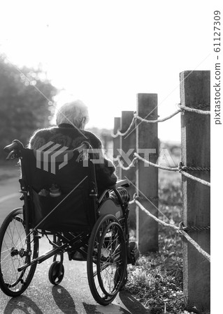 Picture of lonely old woman sitting on the wheelchair while looking at sunlight. Picture of lonely old woman sitting on the wheelchair while looking at sunlight. 61127309