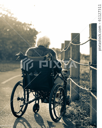 Picture of lonely old woman sitting on the wheelchair while looking at sunlight. Picture of lonely old woman sitting on the wheelchair while looking at sunlight. 61127311