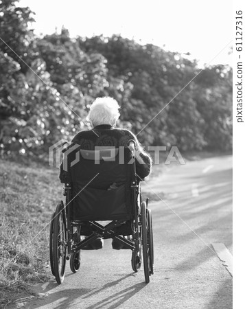Picture of lonely old woman sitting on the wheelchair while looking at sunlight. Picture of lonely old woman sitting on the wheelchair while looking at sunlight. 61127316