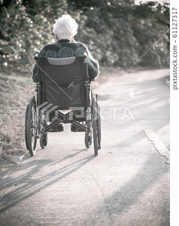 Picture of lonely old woman sitting on the wheelchair while looking at sunlight. Picture of lonely old woman sitting on the wheelchair while looking at sunlight. 61127317