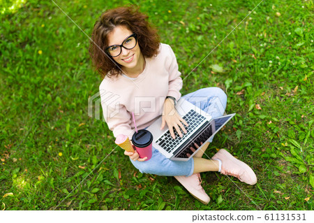 freelance concept. girl sitting on grass with laptop and coffee freelance concept. girl sitting on grass with laptop and coffee 61131531
