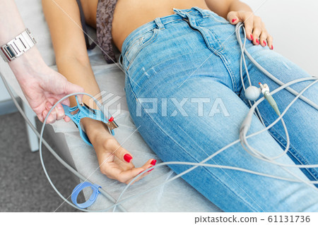 The doctor attaches the electrodes of the ECG pegs 61131736