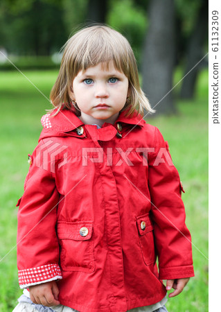 Serious or sad baby girl in red. Caucasian blonde 61132309