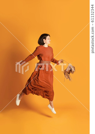 Pleased european girl jumping on yellow 61132344