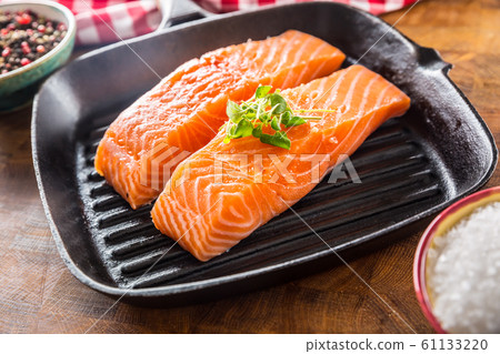 Fresh raw salmon fillets served in cast iron grill 61133220