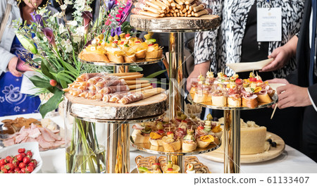 Businesspeople at banquet lunch break at business conference meeting. Assortment of canapes and finger food on the table. 61133407