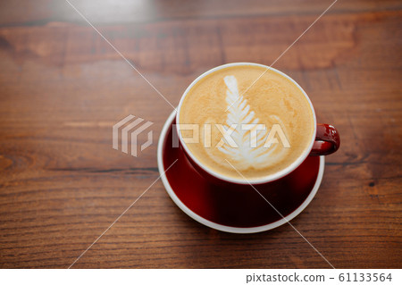 Cappuccino in red cup on a wooden table overview. 61133564