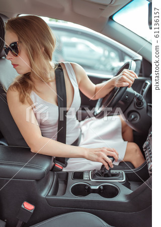 woman driving car, looking rear window, reversing, parking shopping center, checking in a car in a garage. Summer girl in a dress. Automatic transmission. Vehicle interior. 61136157