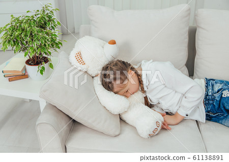 Sweet charming kid is lovely sleeping on her big white teddy-bear. 61138891
