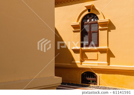 Yellow French Colonial building facade and artisan window frame 61141591