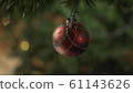 a glass toy hangs on a decorated Christmas tree, against the background of flashing lights 61143626